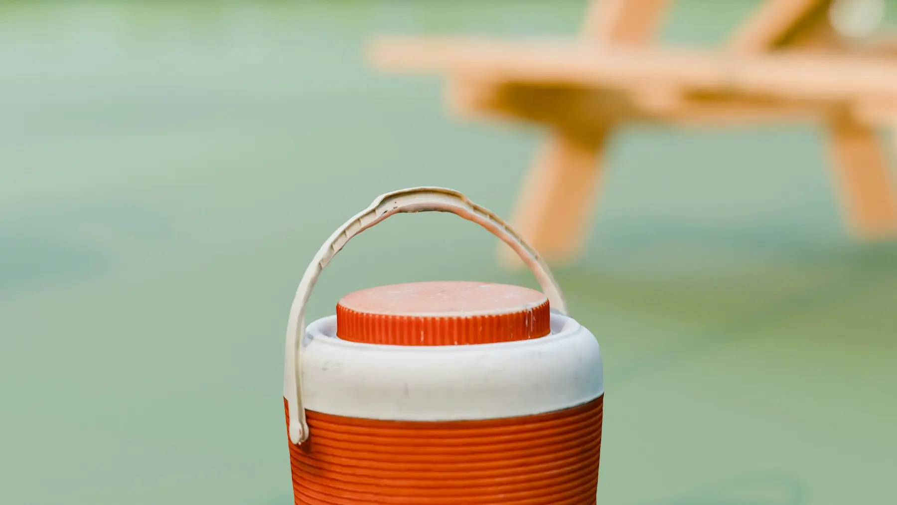 An orange-and-white insulated cooler at an outdoor picnic area