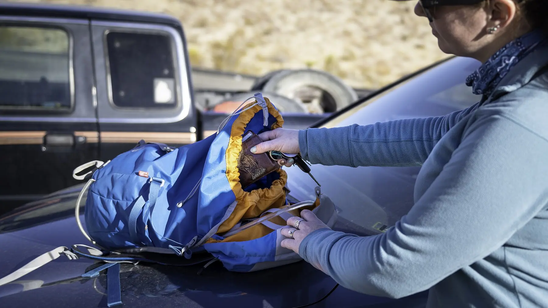 A hiker packing a blue daypack before setting out on a trail