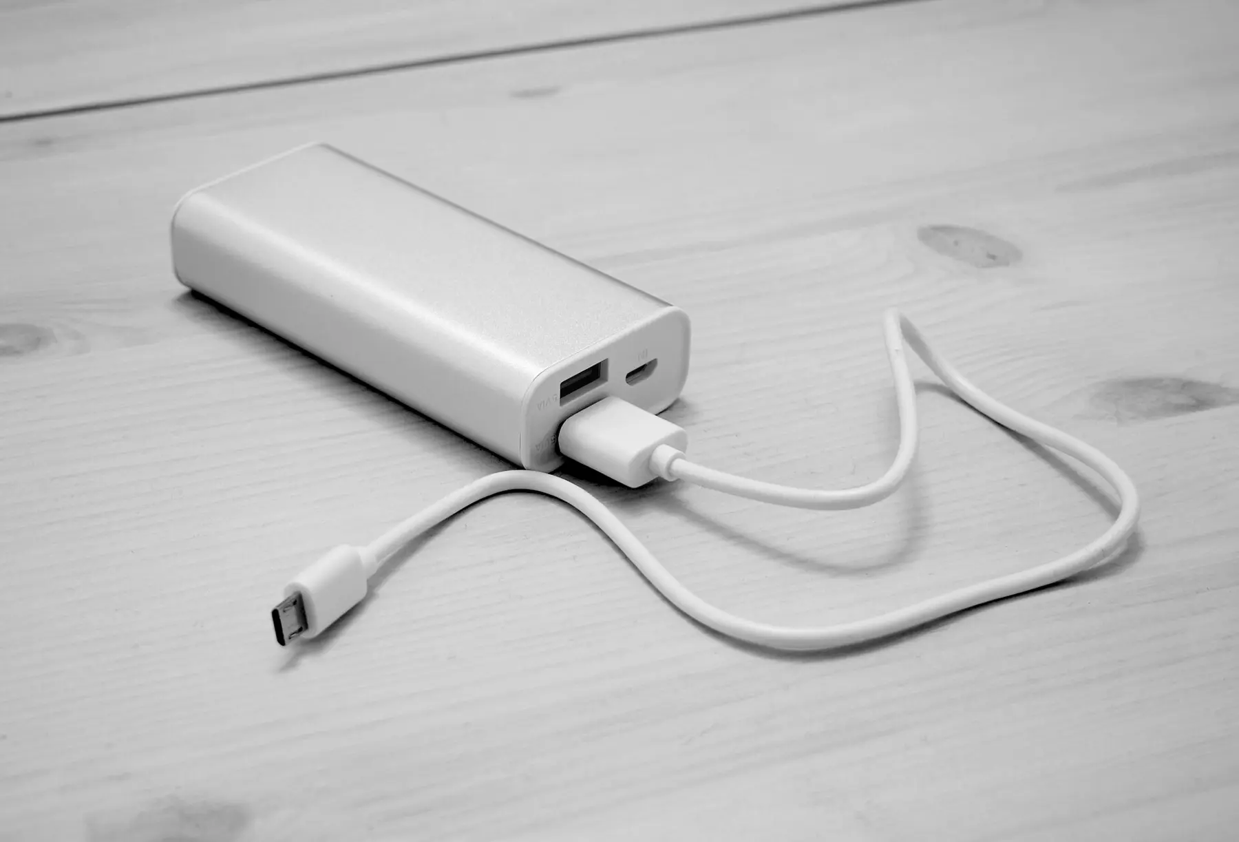 A portable phone power bank connected to a charging cable on a table