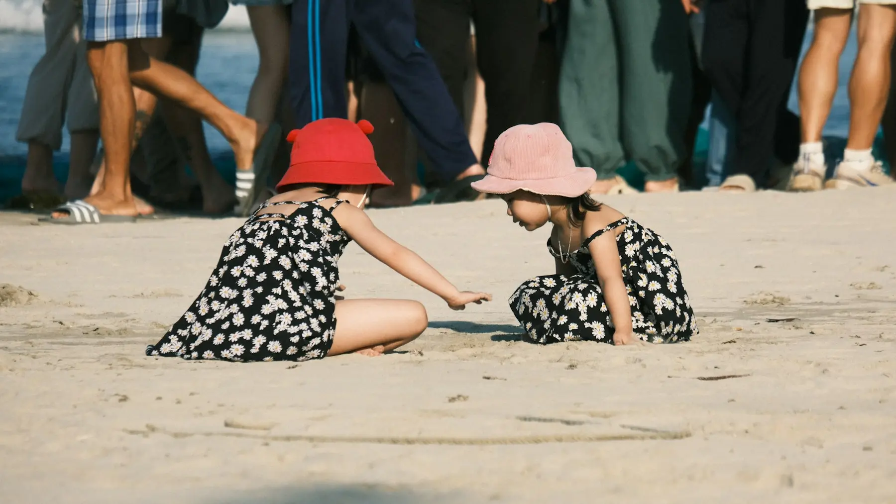 Two children wearing broad-brimmed sun hats while playing on a beach